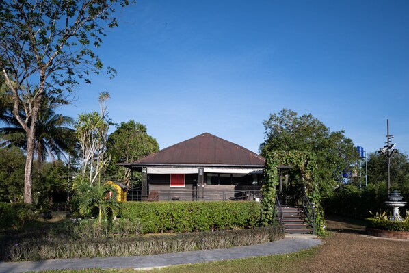 A modern building with a brown roof, surrounded by lush greenery and a clear blue sky. - ST Resort (Ranong)
