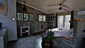 A modern bedroom with a bed, a ceiling fan, a potted plant, and a shower area. - Villa La Mercy Chalet (La Mercy)