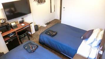 Une chambre d’hôtel avec deux lits, un bureau avec un ordinateur, une télévision et un porte-chaussures.