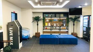 A lobby with a reception desk, a blue seating area, and a wall-mounted TV.