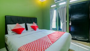 A hotel room with a bed, green walls, a black door, and an air conditioning unit. - OYO 1014 Bettah Coba 2 Sukabumi (Sukabumi)