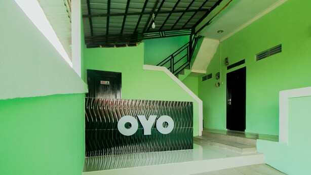 A reception area with a green wall and a black and white sign that reads "OYO". - OYO 1014 Bettah Coba 2 Sukabumi (Sukabumi)