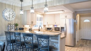 A kitchen with a large island, bar stools, a clock, and modern appliances. - FREE USE OF OUR 2022 23’ TRITOON EVERY RENTAL DAY
May 1st- Oct 31st (Albemarle)