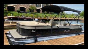A pontoon boat docked at a marina with a covered seating area, a cabin, and a wakeboard. - FREE USE OF OUR 2022 23’ TRITOON EVERY RENTAL DAY
May 1st- Oct 31st (Albemarle)