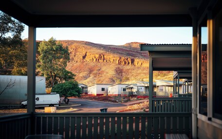 A view from a covered porch overlooking a campground with RVs, mobile homes, and a mountainous backdrop.