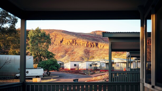 A view from a covered porch overlooking a campground with RVs, mobile homes, and a mountainous backdrop. - Tom Price Tourist Park (Tom Price)