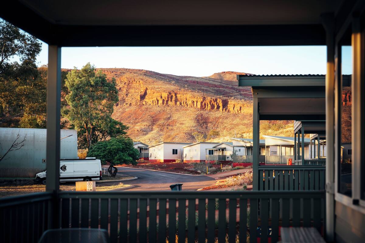A view from a covered porch overlooking a campground with RVs, mobile homes, and a mountainous backdrop.
