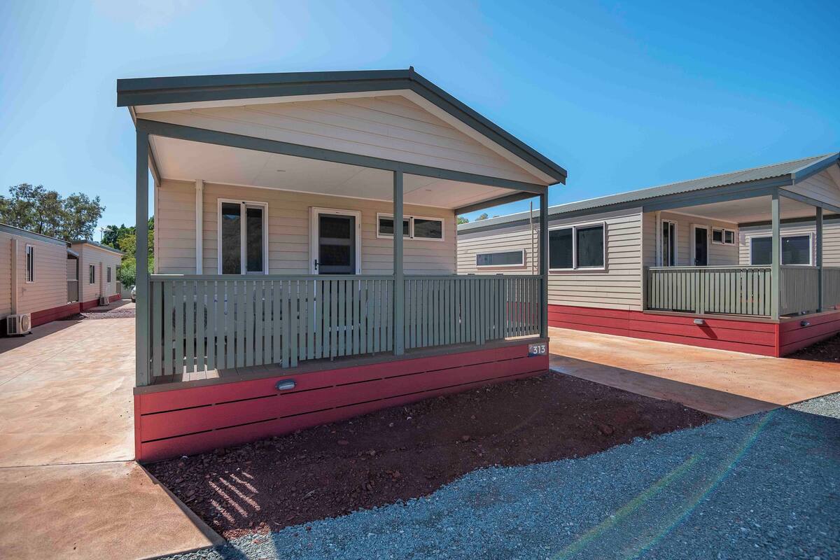 A mobile home with a covered porch and a red base.