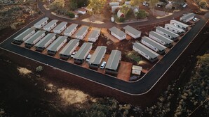 An aerial view of a caravan park with multiple caravan sites, surrounded by trees and hills. - Tom Price Tourist Park (Tom Price)