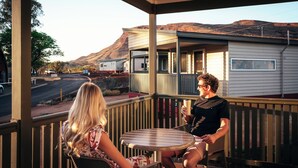 A covered outdoor seating area with a view of a road and hills. - Tom Price Tourist Park (Tom Price)
