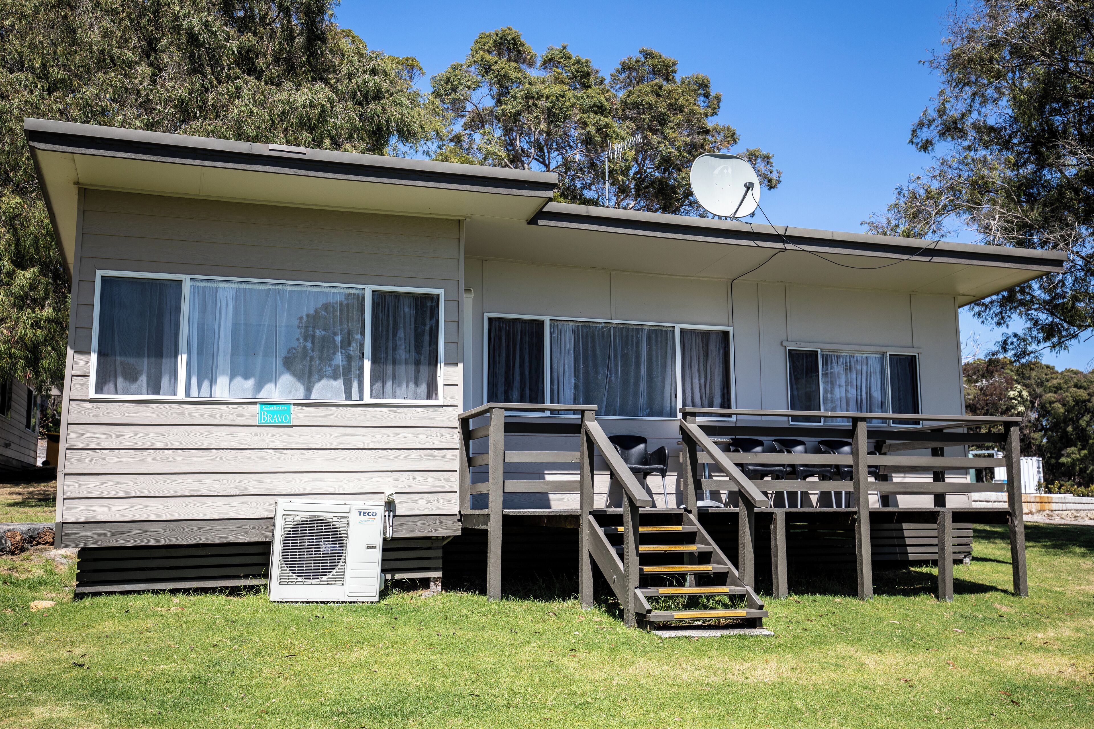 A single-story mobile home with a covered porch and a satellite dish.