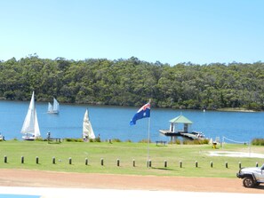 A lakeside view with sailboats, a flag, and a small gazebo.