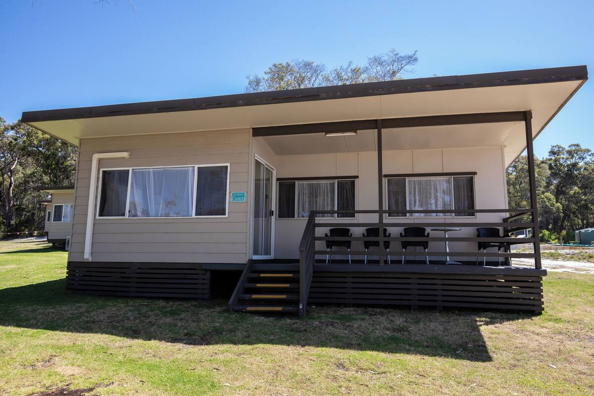 A single-story mobile home with a covered porch and a small set of stairs leading to the entrance.