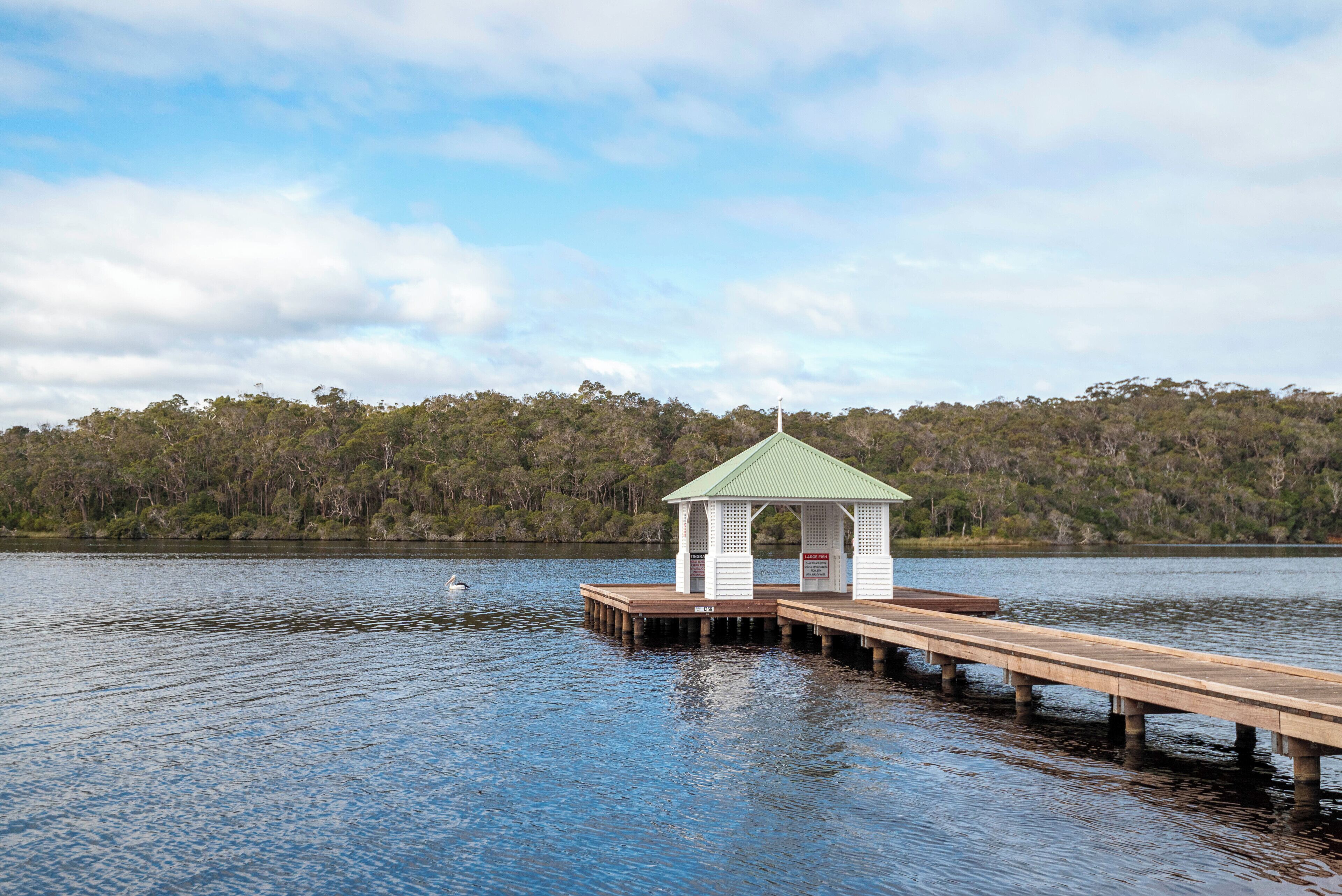 A wooden pier extending into a lake with a gazebo structure at the end.
