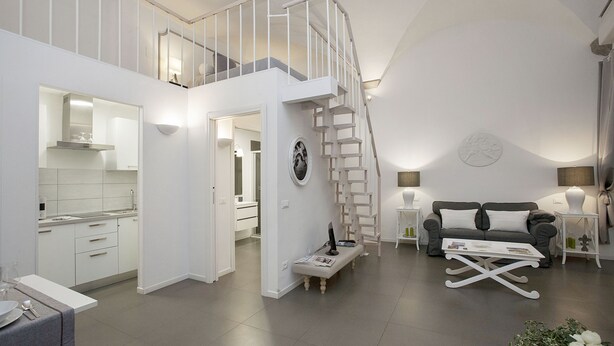 A modern living space with a kitchen, dining area, and a staircase leading to an upper level. - La Casa Bianca: Charming apartment close  S.Spirito Square (Firenze)