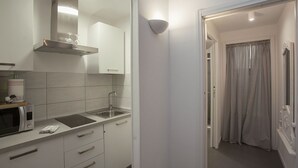 A modern kitchen with white cabinets, a stainless steel range hood, a microwave, and a sink. - La Casa Bianca: Charming apartment close  S.Spirito Square (Firenze)