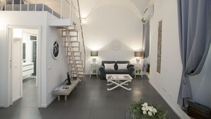 A modern living room with a staircase, a sofa, a coffee table, and a small side table. - La Casa Bianca: Charming apartment close  S.Spirito Square (Firenze)