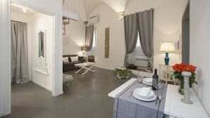 A spacious living area with a dining table set for two, a sofa, and a staircase leading to an upper level. - La Casa Bianca: Charming apartment close  S.Spirito Square (Firenze)