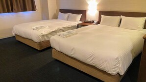 Une chambre d’hôtel avec deux lits, une table de chevet et une lampe fixée au mur.