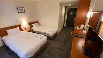 Habitación de hotel con dos camas, un escritorio con computadora, un televisor y un cuadro en la pared.
