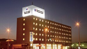 Un grand hôtel à plusieurs étages, doté d’une enseigne et de fenêtres illuminées, situé à proximité d’un aéroport.