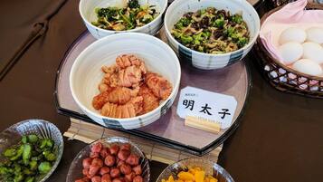A table with various dishes, including a bowl of fried chicken, vegetables, and other food items.