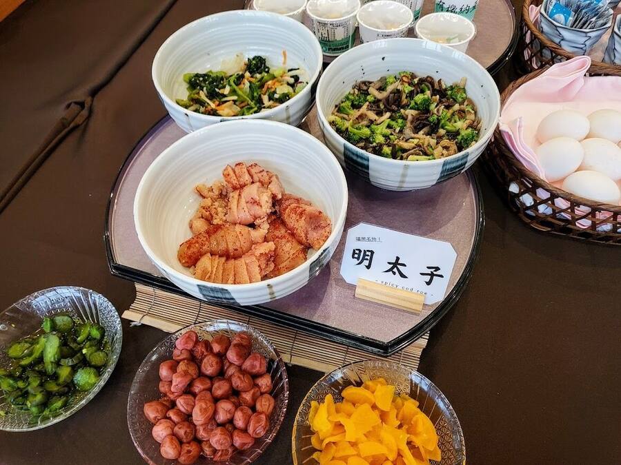 A table with various dishes, including a bowl of fried chicken, vegetables, and other food items.