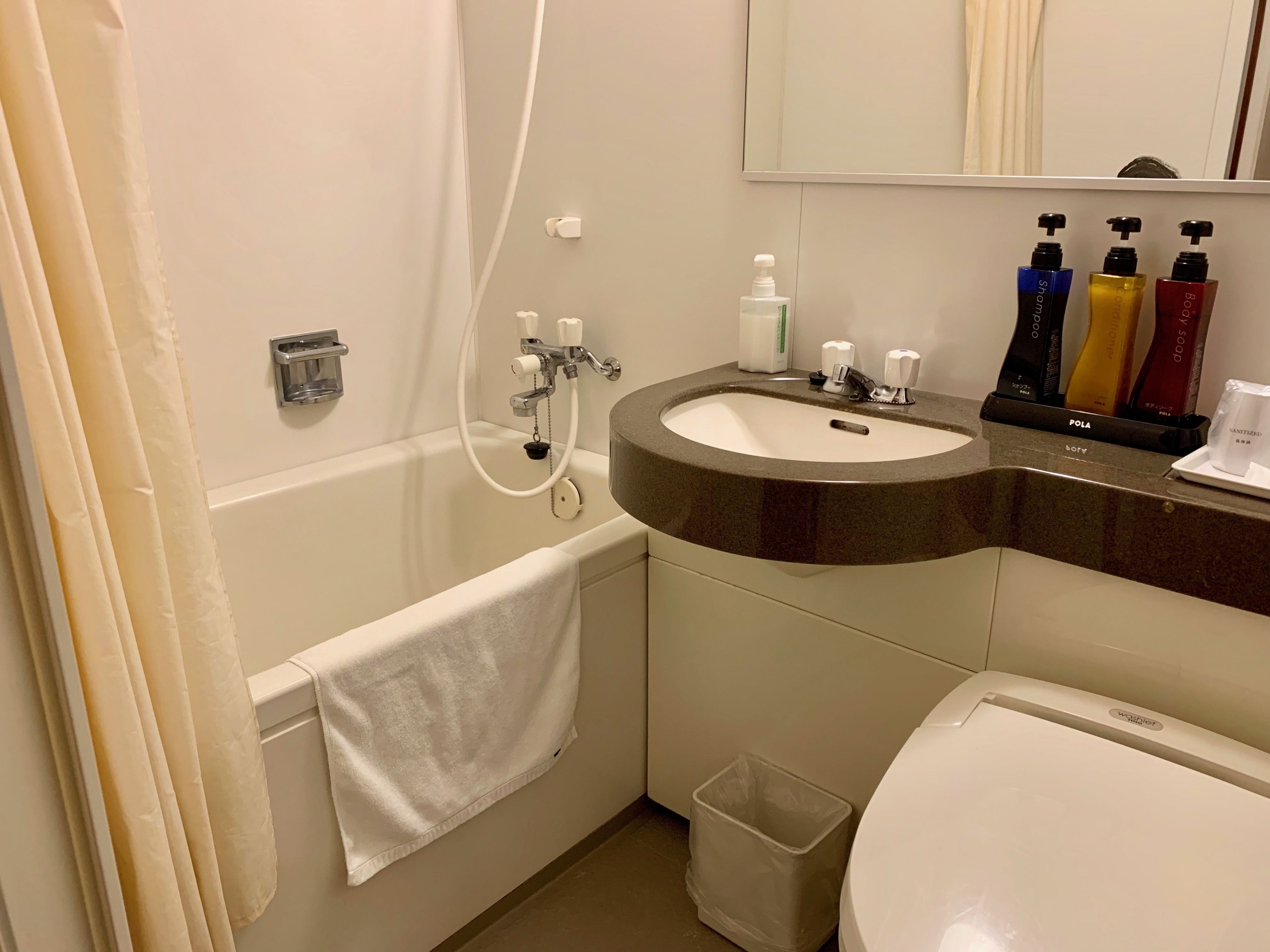Uma casa de banho com banheira, lavatório com dispensadores de sabonete líquido e sanita.