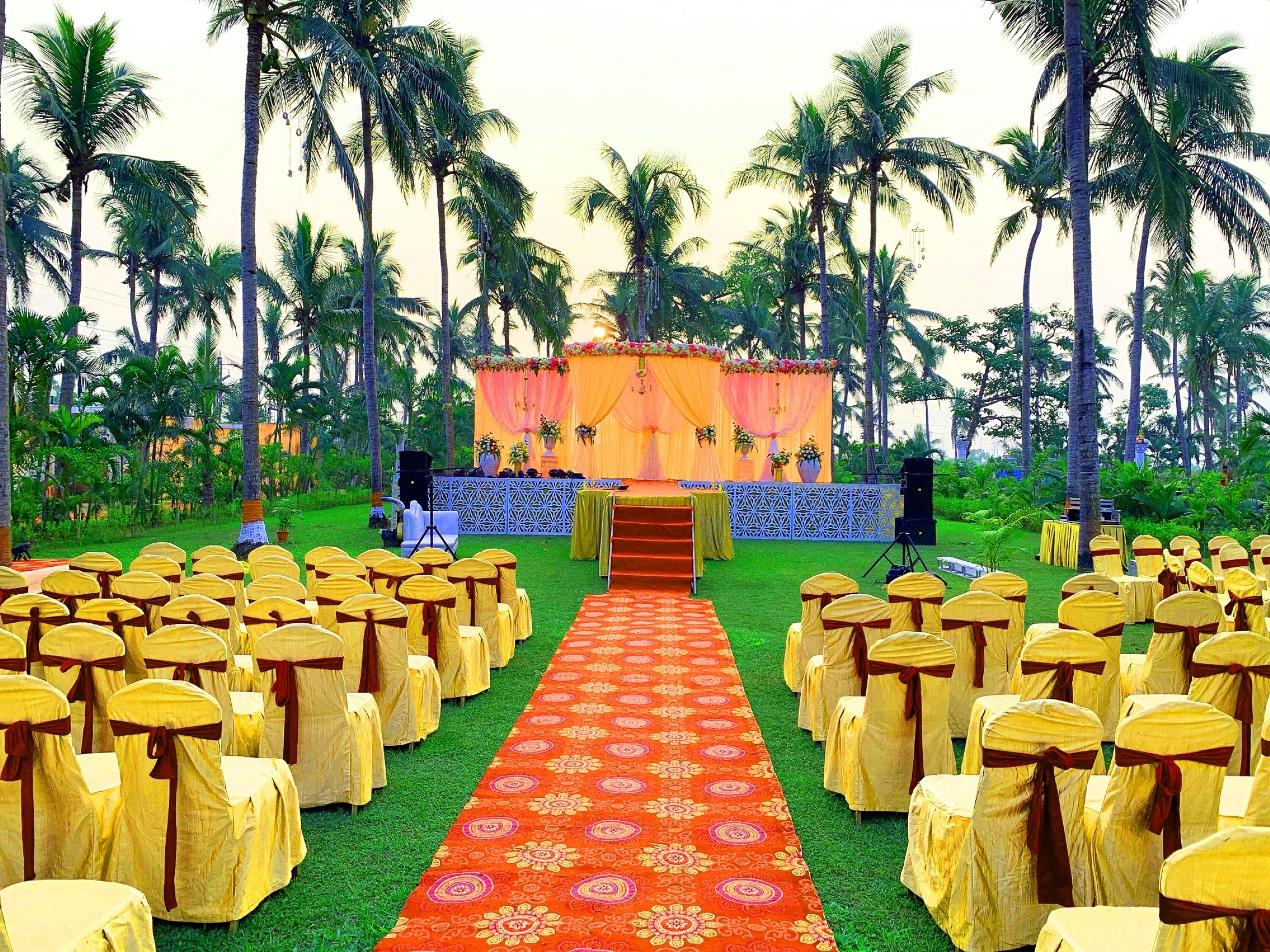 An outdoor event space with rows of chairs and a stage with a floral backdrop.