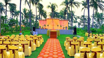 An outdoor event space with rows of chairs and a stage with a floral backdrop.