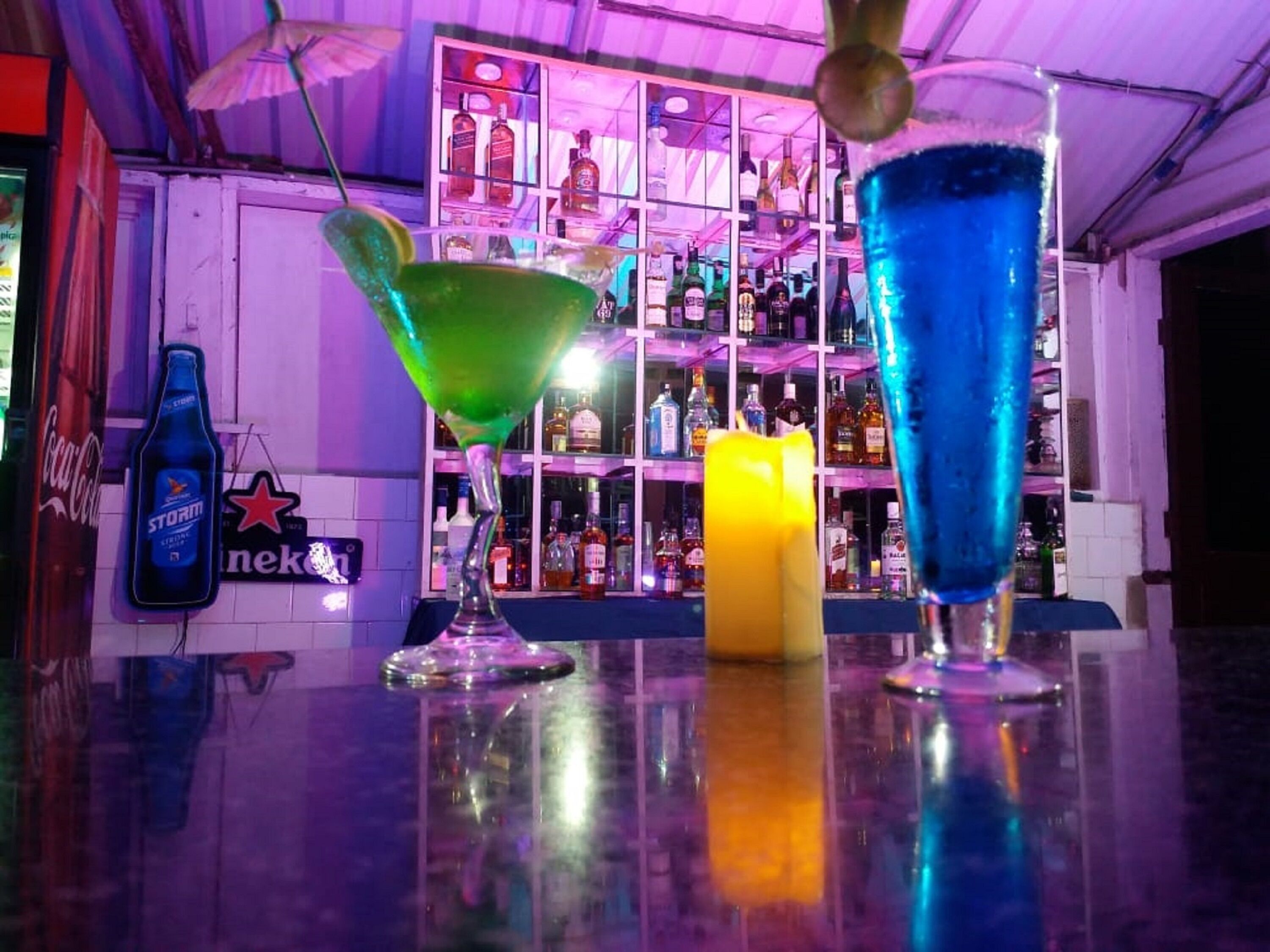 Una zona de bar con dos vasos de martini, una botella de Storm y un letrero de neón.
