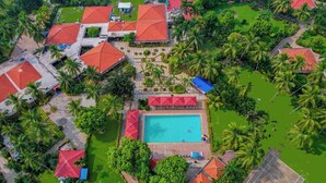 An aerial view of a resort with multiple buildings, a swimming pool, and surrounding greenery. - Toshali Sands Nature Escape (Puri)