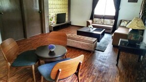 A living room with a sofa, chairs, a coffee table, and a television. - Borneo Tribal Village (Kuching)