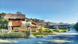 A resort with traditional wooden structures, a paved pathway, and a landscaped garden. - Borneo Tribal Village (Kuching)