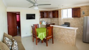 Uma cozinha compacta com área de refeições, um ventilador de teto e uma TV na parede.