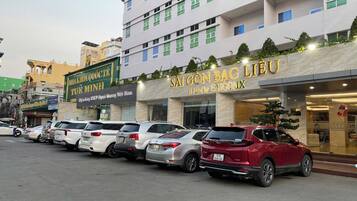 Un hotel con fachada moderna, varios pisos y una fila de coches estacionados al frente.