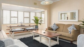 Sala de estar com sofá, mesa de centro, um banco e um vaso de planta.