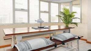 Uma área de refeições com uma mesa de madeira, bancos e um vaso com planta.