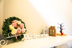 A welcome sign with a wreath of pink and yellow roses on a white shelf. - Wamikyo Homy (Kyoto)