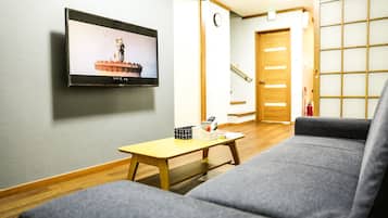 A modern living room with a grey sofa, a wooden coffee table with a remote control, and a framed picture on the wall.
