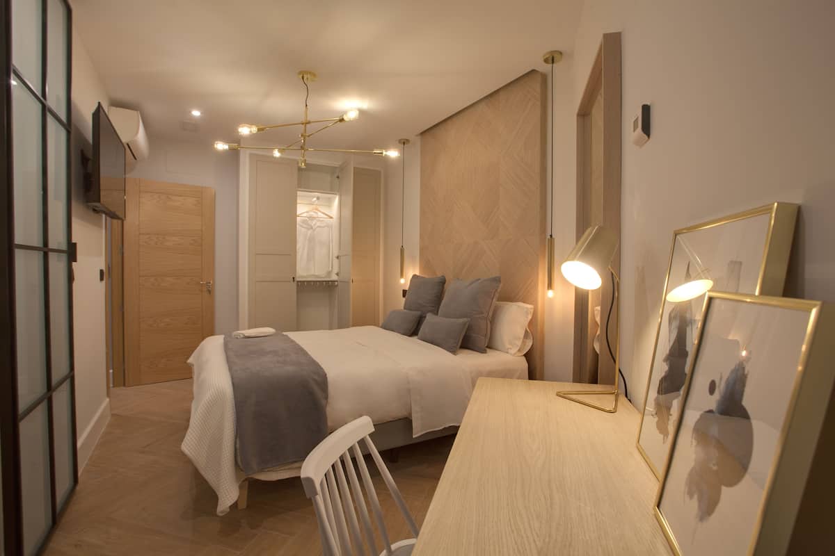 Un dormitorio con cama, mesita de noche, silla y espejo.