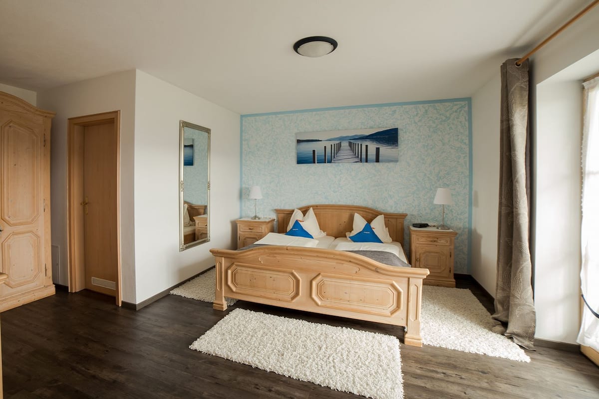 Un dormitorio con una cama de madera, mesitas de noche, un espejo y un cuadro en la pared.