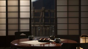 A traditional Japanese room with tatami flooring, a low table with a tea set, and a shoji screen door.