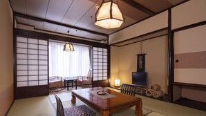 A traditional Japanese room with tatami flooring, a low wooden table, a television, and a sliding door.