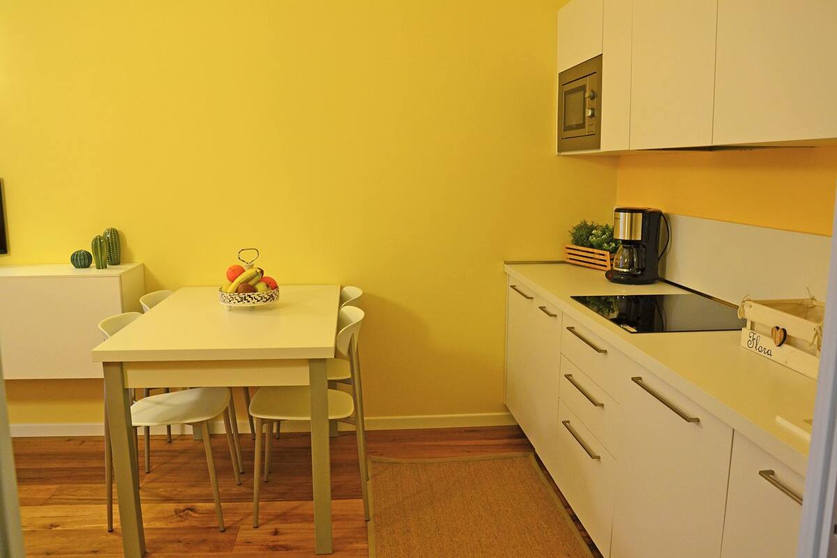 A compact kitchen with a dining table, chairs, a microwave, and a coffee maker.