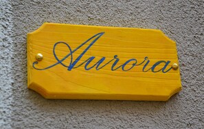 Une enseigne en bois sur laquelle est inscrit le mot « Aurora » en lettres cursives.
