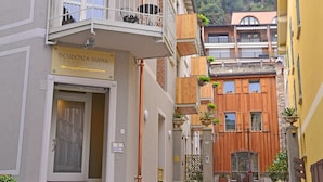 A narrow street with a building labeled "RESIDENZA DIANA APARTMENTS" featuring balconies with plants, a wrought iron gate, and a stone facade. - Residenza Diana (Toscolano Maderno)