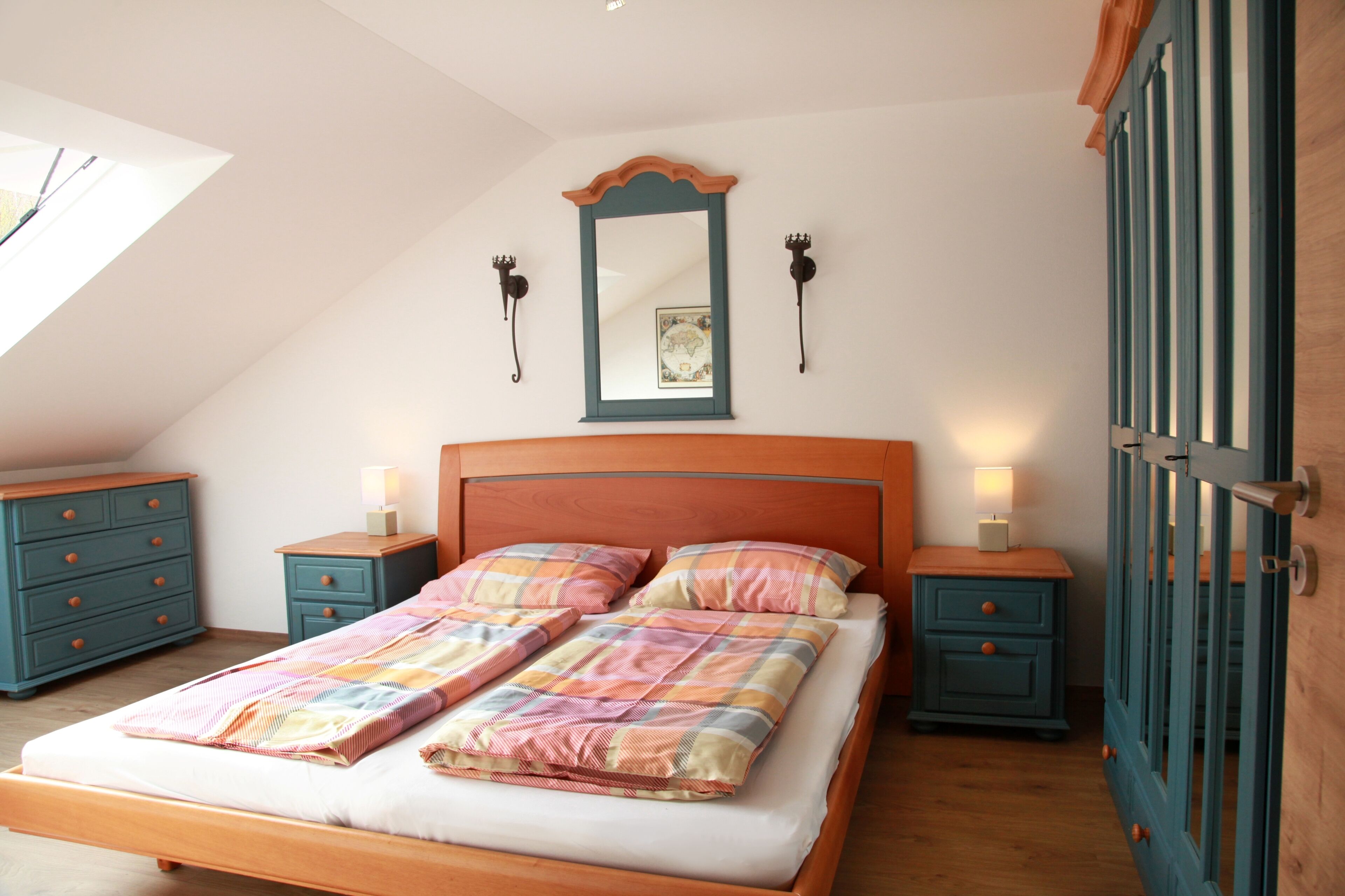 Une chambre à coucher avec un lit en bois, deux tables de chevet, un miroir et une armoire.