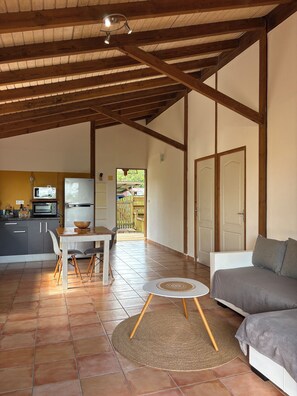 A spacious living area with a dining table, sofa, and kitchen in the background.