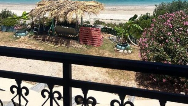 A beach view with a thatched hut and a red crate, overlooking the ocean. - Michaela (Kefalonia)